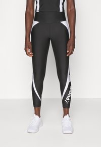 Black athletic leggings with white accents and logo, featuring a high waistband and a form-fitting design, made from stretch material.