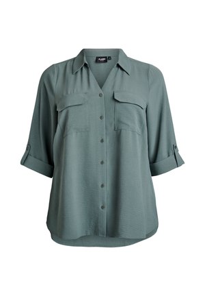 Košile s krátkým rukávem a zapínáním na knoflíky v tlumené zelené barvě. Má dvě náprsní kapsy, límeček a mírně zaoblený spodní okraj. Jemná, lehká látka.