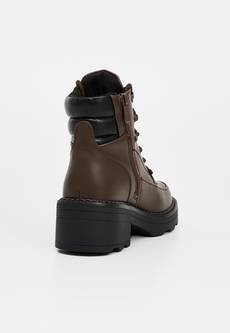 Braune Leder-Stiefeletten mit einem schwarzen gepolsterten Kragen, seitlichem Reißverschluss, Schnürung auf der Vorderseite und dicken Gummisohlen. Strukturierte Oberflächendetails.