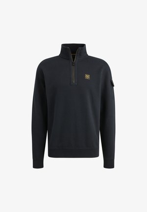 Sweat-shirt zippé navy avec col montant, poignets côtelés et un petit patch logo doré sur la poitrine. Texture de tissu lisse.