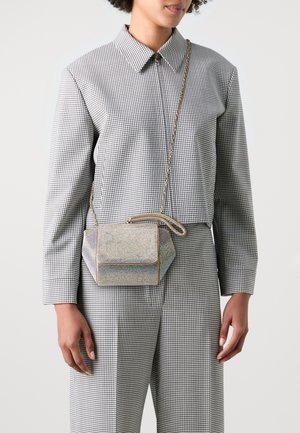 Petit sac géométrique en matière holographique avec ferrures dorées, présentant un design structuré et une bandoulière chaîne amovible.