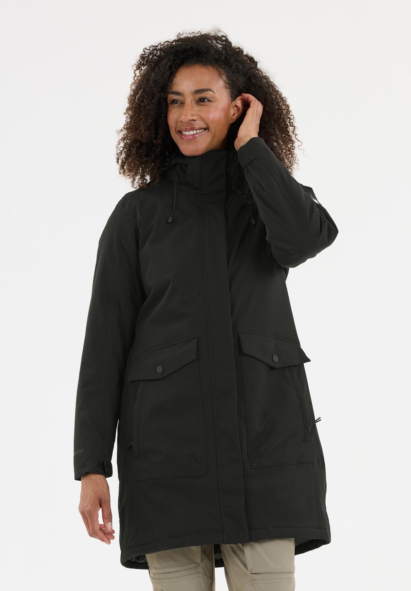 Zwarte, lange parka met lange mouwen en een hoge kraag, verstelbare trekkoordcapuchon en twee grote voorzakken. Gemaakt van glad, weerbestendig materiaal.