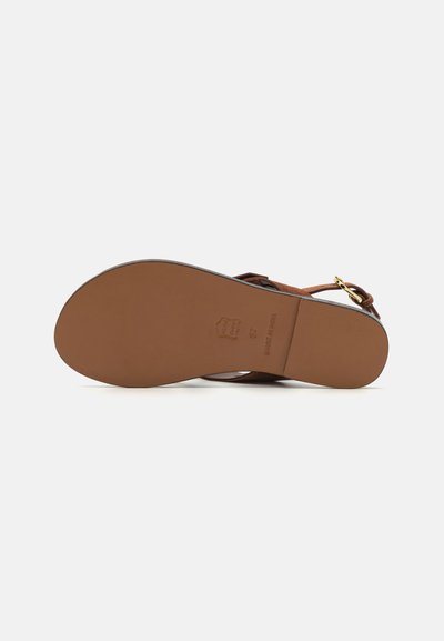 Brown suede sandal with a flat sole, features a gold buckle accent and a rounded toe. The sole is light brown with embossed branding.