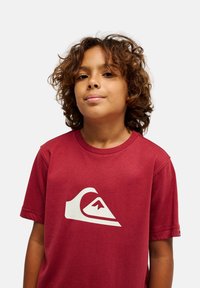 Κόκκινο βαμβακερό μπλουζάκι με στρογγυλή λαιμόκοψη και κοντά μανίκια. Διαθέτει ένα εμφανές λευκό λογότυπο κύματος στο μπροστινό μέρος. Απαλή, casual εφαρμογή.