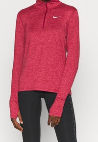 Maglia sportiva rossa a maniche lunghe con colletto alto, zip a un quarto e tessuto testurizzato. Presenta un piccolo logo argento sul petto.