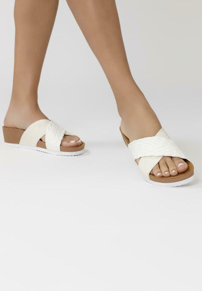 Sandales compensées blanches avec des sangles en textile tressé, dessus texturé et semelle intérieure beige. Semelle en caoutchouc blanche unie avec une légère élévation.