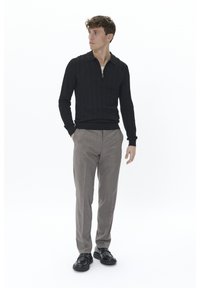 Pulover negru tricotat cu fermoar la un sfert și textură cu nervuri, asortat cu pantaloni gri cu model și pantofi negri cu șireturi.