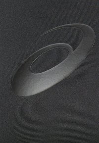Tela negra con un patrón texturizado, que presenta un logo ovalado negro mate. El diseño es elegante y aerodinámico, destacando un enfoque en el rendimiento.