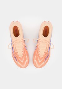 Jasnoczerwone i niebieskie buty sportowe z teksturowaną cholewką, z zygzakowatym wzorem, smukłą sylwetką i tradycyjnym systemem sznurowania.