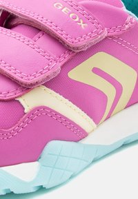 Ροζ παιδικό αθλητικό παπούτσι με γαλάζια σόλα, λουράκια με  βέλκρο, μπεζ λεπτομέρειες και το λογότυπο "GEOX" στο πάνω λουράκι.
