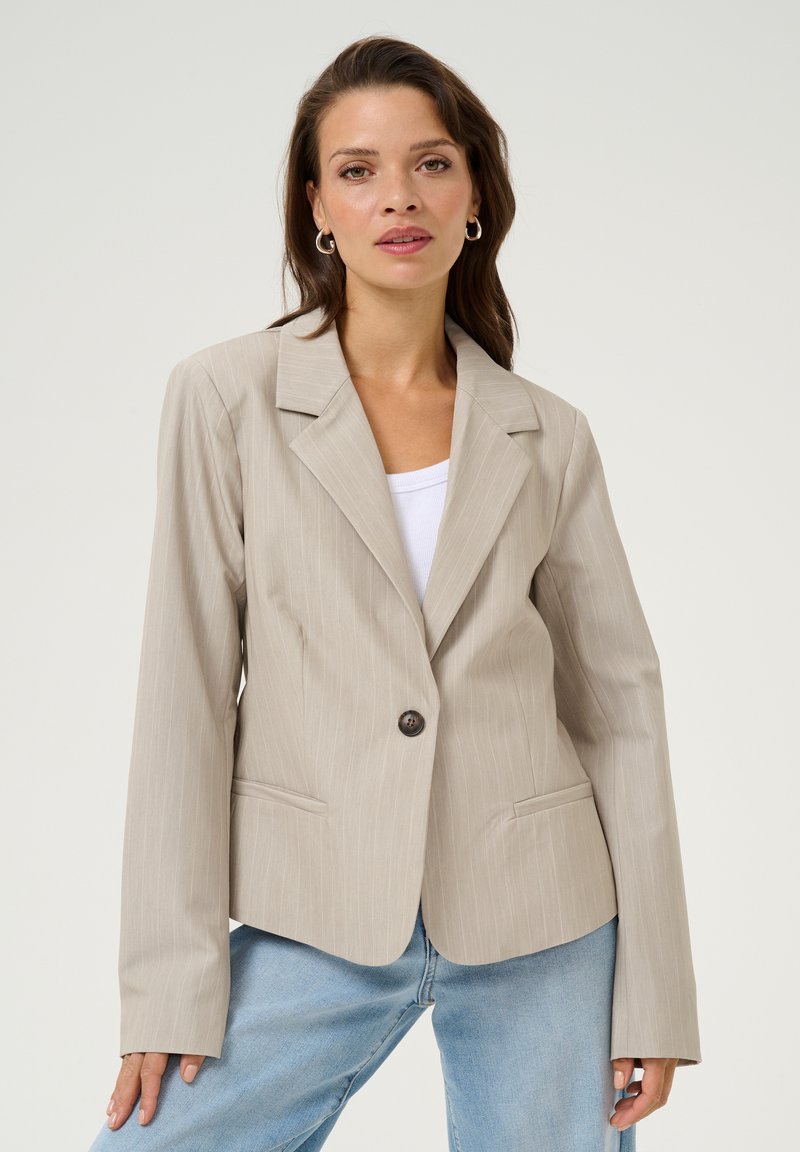 Světlý béžový blazer s jemným proužkem vyrobený z hladké tkaniny, s jedním knoflíkem na zapínání, klopovými límci a kapsami s klopou.