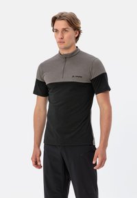 Chemise à manches courtes avec col zippé en gris et noir, fabriquée en tissu doux avec des blocs de couleur contrastants, arborant un petit logo sur la poitrine.