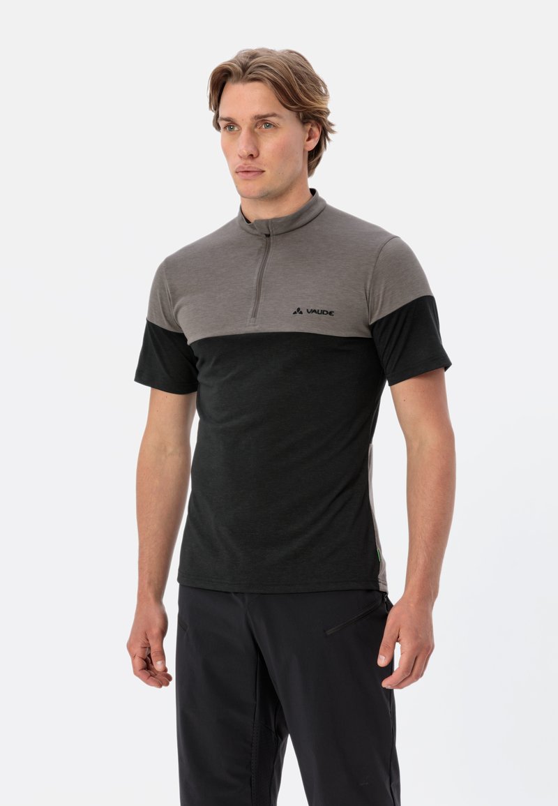 Chemise à manches courtes avec col zippé en gris et noir, fabriquée en tissu doux avec des blocs de couleur contrastants, arborant un petit logo sur la poitrine.