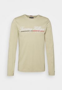 Beige Langarmshirt aus Baumwollmischung, mit "Tommy Hilfiger" Logo in Weiß mit roten und schwarzen Akzenten, Rundhalsausschnitt und normaler Passform.