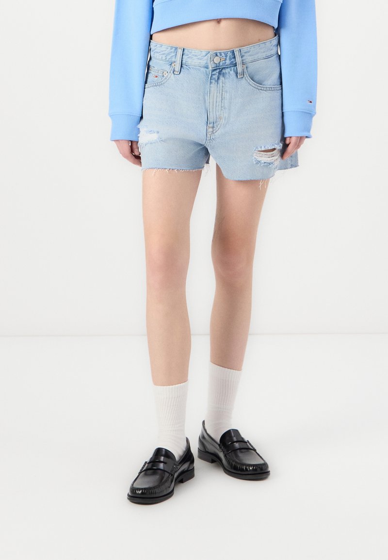 Light blue denim shorts with frayed hems and distressed details, paired with black loafers and white knee-length socks.