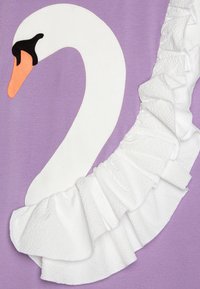 Violeta tekstila ar baltu rīkojumā un aplikācijas pīļu dizainu, kuram ir melna acs un oranža knābis.