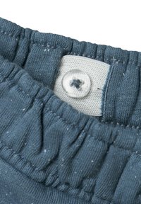 Cintura de algodón azul con textura fruncida y banda elástica; presenta un botón transparente y un parche de tela blanca con un pequeño diseño de flor.