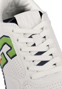 Baskets en cuir blanc avec des accents verts et bleus, présentant une texture perforée, des lacets blancs plats et une languette de marque marquée "GAP."