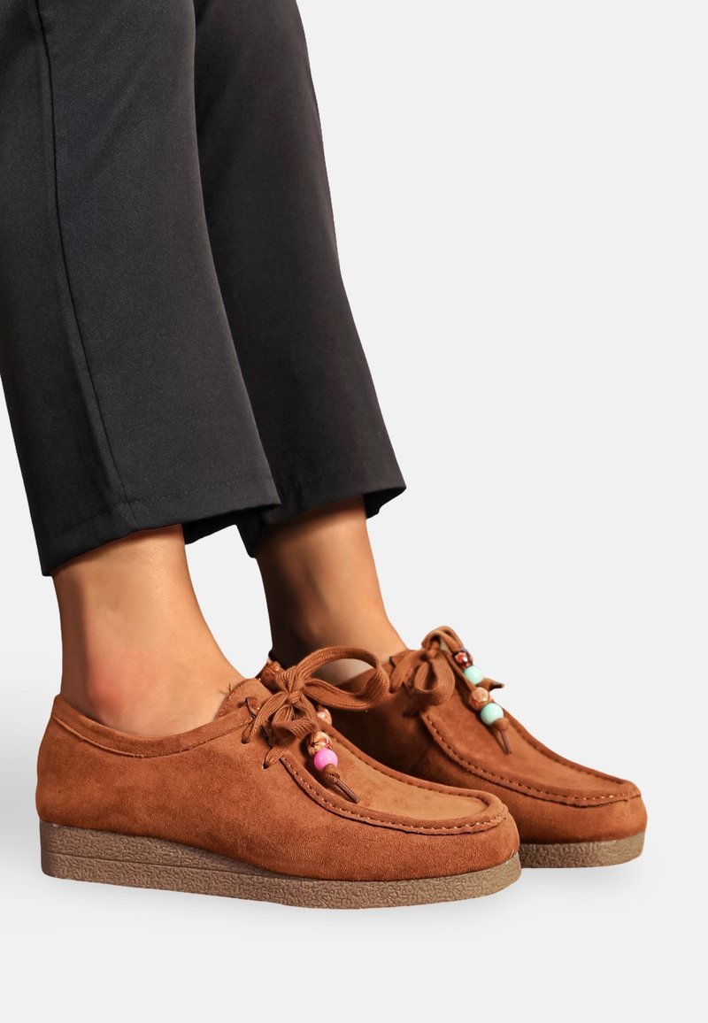 Chaussures en cuir suédé marron avec des bouts arrondis, à lacets, et des accents de perles colorées sur les lacets. Les semelles en caoutchouc texturé améliorent l'adhérence et le confort.