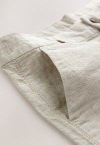 Light beige linen shorts with a textured fabric, featuring a side pocket, visible stitching, and a relaxed cut.