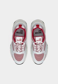 Λευκά και κόκκινα αθλητικά παπούτσια Love Moschino με δίχτυνο ύφασμα, παχιά σόλα και επωνυμη επένδυση εσωτερικά και στη γλώσσα, φωτογραφημένα από πάνω σε λευκό φόντο.