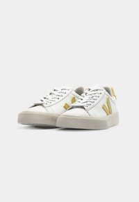 Tênis de couro branco com detalhes em amarelo, sola de borracha texturizada e um design clássico de atacadores. Os calçados apresentam um estilo minimalista.