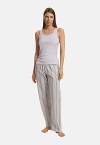 Světle fialový tílko se zaobleným výstřihem, doplněné pruhovanými, volně střiženými pyžamovými kalhotami se svislými fialovými a šedými pruhy.
