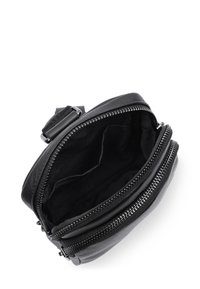 Borsa in pelle nera con apertura con zip, superficie liscia, doppio scomparto e una tracolla regolabile robusta. Interno foderato in tessuto morbido.