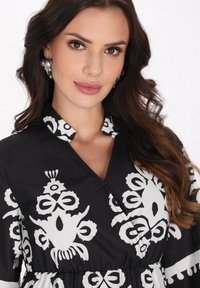 Rochie neagră cu modele florale albe îndrăznețe, guler și talie strânsă. Material neted cu un finisaj lucios și un design elegant.
