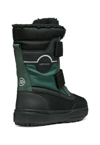Botas de invierno impermeables en negro y verde oscuro con superficie texturizada, correas de Velcro y un suave collar similar a piel. Presentan un logotipo circular.