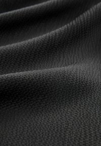 Strukturiertes dunkelgraues Gewebe mit einem dezenten Webmuster, das eine glatte Oberfläche und einen weichen Fall aufweist und seine leichte Qualität hervorhebt.