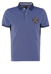 Polo bleu à manches courtes avec col et bord de manches bleu foncé, deux boutons et écusson rond avec le logo Hilfiger New York sur la poitrine gauche.