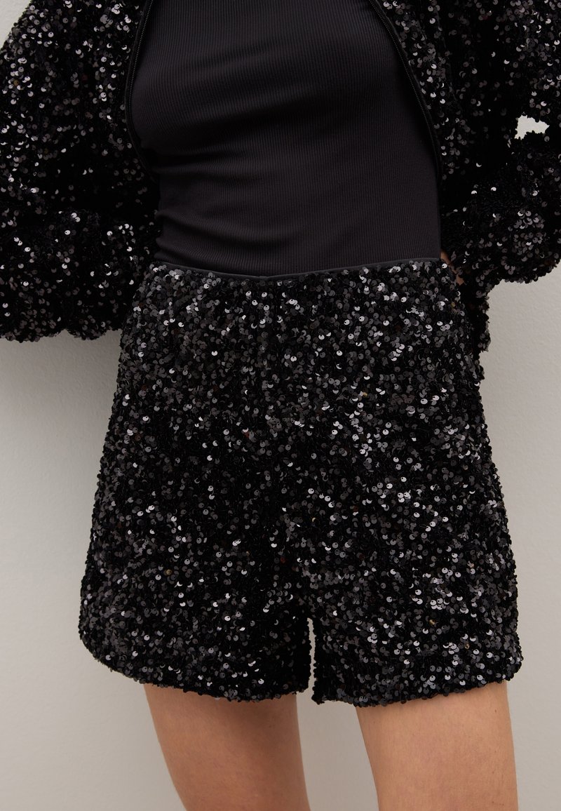 Black sequin shorts featuring a textured, shiny surface. The pattern consists of densely arranged sequins, creating a reflective look.