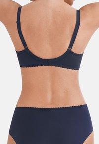 Marineblauwe bh met verstelbare bandjes, geschulpte randen en een haak- en oogsluiting achteraan. Glad stofgevoel.