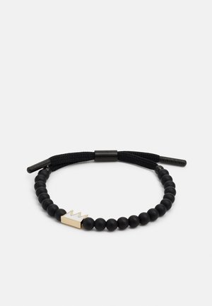 Bracelet de perles noires avec un accent de couronne dorée, présentant une finition texturée et un cordon ajustable pour personnaliser la taille.