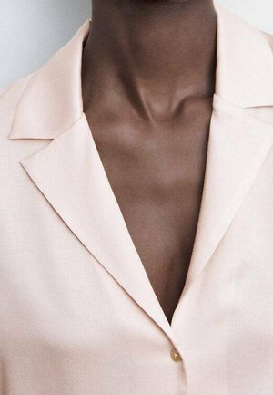 Hellrosa Blazer mit Reverskragen, Ein-Knopf-Verschluss und glatter Textur. Nahaufnahme, die sich auf den Ausschnitt und die Details des Stoffes konzentriert.