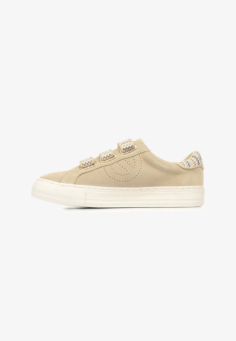 Beige suede sneaker with a rounded toe, three decorative straps, and a patterned accent at the heel. White rubber sole with textured detailing.