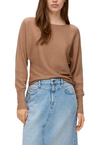Beige gerippter Strickpullover mit weitem Bootsausschnitt und langen Ärmeln, kombiniert mit einem hoch taillierten, hellblauen Jeansrock mit aufgesetzten Taschen.