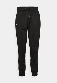 Pantalon de survêtement noir fuselé avec taille élastique, fermeture à cordon, poignets côtelés et petit logo blanc sur la cuisse gauche.