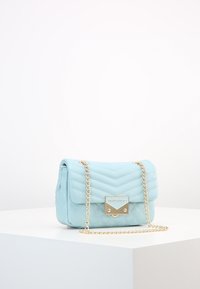 Světle modrá prošívaná kabelka s zlatým řetízkovým popruhem. Disponuje magnetickým uzávěrem a zlatým kovovým detailem. Kompaktní obdélníkový tvar.