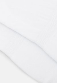 Vita bomullssockor med en slät yta och ribbade muddar. Tyget verkar lätt med en enkel design och inga synliga mönster.