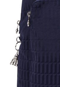 Mörkblå texturerad väska med en quiltad design, silverfärgad dragkedja och en liten robotcharm fäst vid dragkedjan.