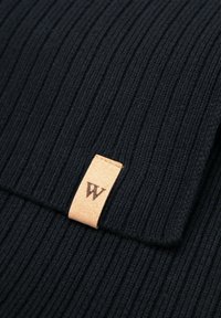 Zwarte gebreide muts met geribbelde textuur en een omgeslagen boord. Heeft een tan leren label met het geperste "W" logo.