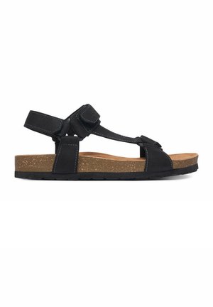 Schwarze offene Sandale mit verstellbaren Riemen, Kork-Fußbett und Gummisohle, im Profil vor weißem Hintergrund gezeigt.
