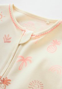 Body pour bébé couleur crème avec imprimés tropicaux roses comprenant des palmiers, des ananas, des soleils, des arcs-en-ciel, et une bordure d'encolure festonnée rose.