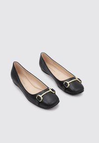 Bailarinas de cuero negro con suela plana, puntera cuadrada y detalles en dorado en la parte delantera. Textura suave con un diseño minimalista.