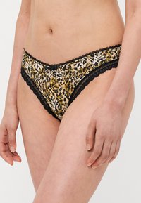 Culottes à imprimé léopard avec une finition satinée et un délicat passepoil en dentelle noire. Le design est taille basse, avec une texture lisse et un ajustement réglable.