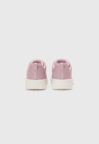 Pink mesh sneakers with a textured finish, white rubber sole, and pull tabs. Showcases a minimalist design and rear branding detail.