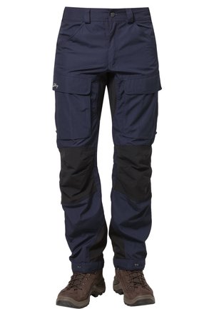 Marineblaue Cargo-Hose mit schwarzen verstärkten Kniepatches, vordere Klappentaschen, Knopfverschluss, getragen mit braunen Wanderschuhen.