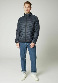 Lengvas juodas pūkinis švarkas su siuvinėta konstrukcija, aukštu apykakle ir priekiu užtraukiamu užtrauktuku. Derinamas su suknotomis džinsinėmis kelnėmis ir baltomis sportinėmis bateliais.